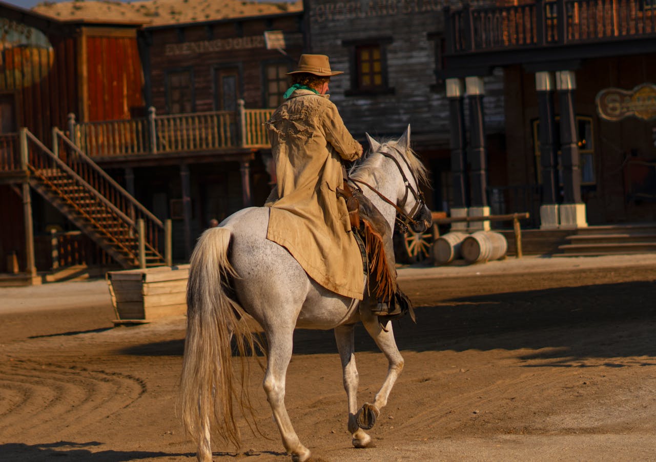 Home A cowboy rides a white horse in Mini Hollywood theme park, Tabernas, Spain, capturing the essence of the Wild West.